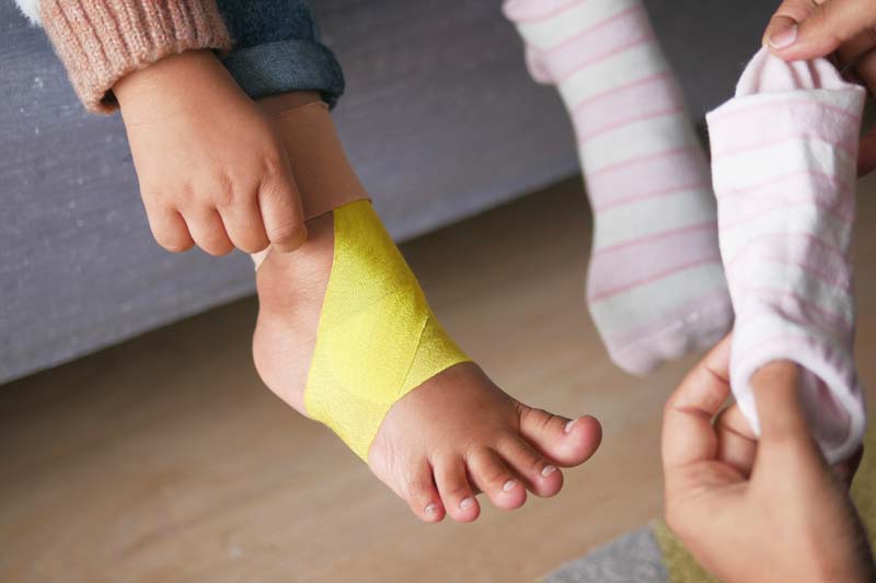 Elastisches therapeutisches gelbes Tape wurde an Kinderfuß angebracht.