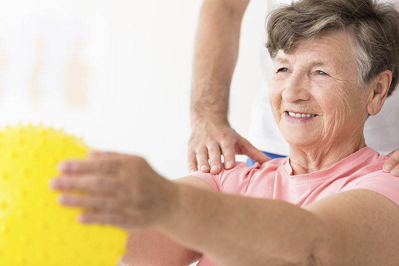 Frau hält Igelball in physiotherapeutischer Übung